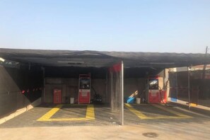 A covered parking area with a fuel pump, a fire extinguisher, and a red emergency phone. - Youyou Boutique Hotel (Xiong County Government Branch) (Xiong County)
