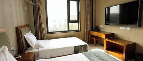 Une chambre d’hôtel avec deux lits, une télévision, un bureau et une fenêtre avec des rideaux.