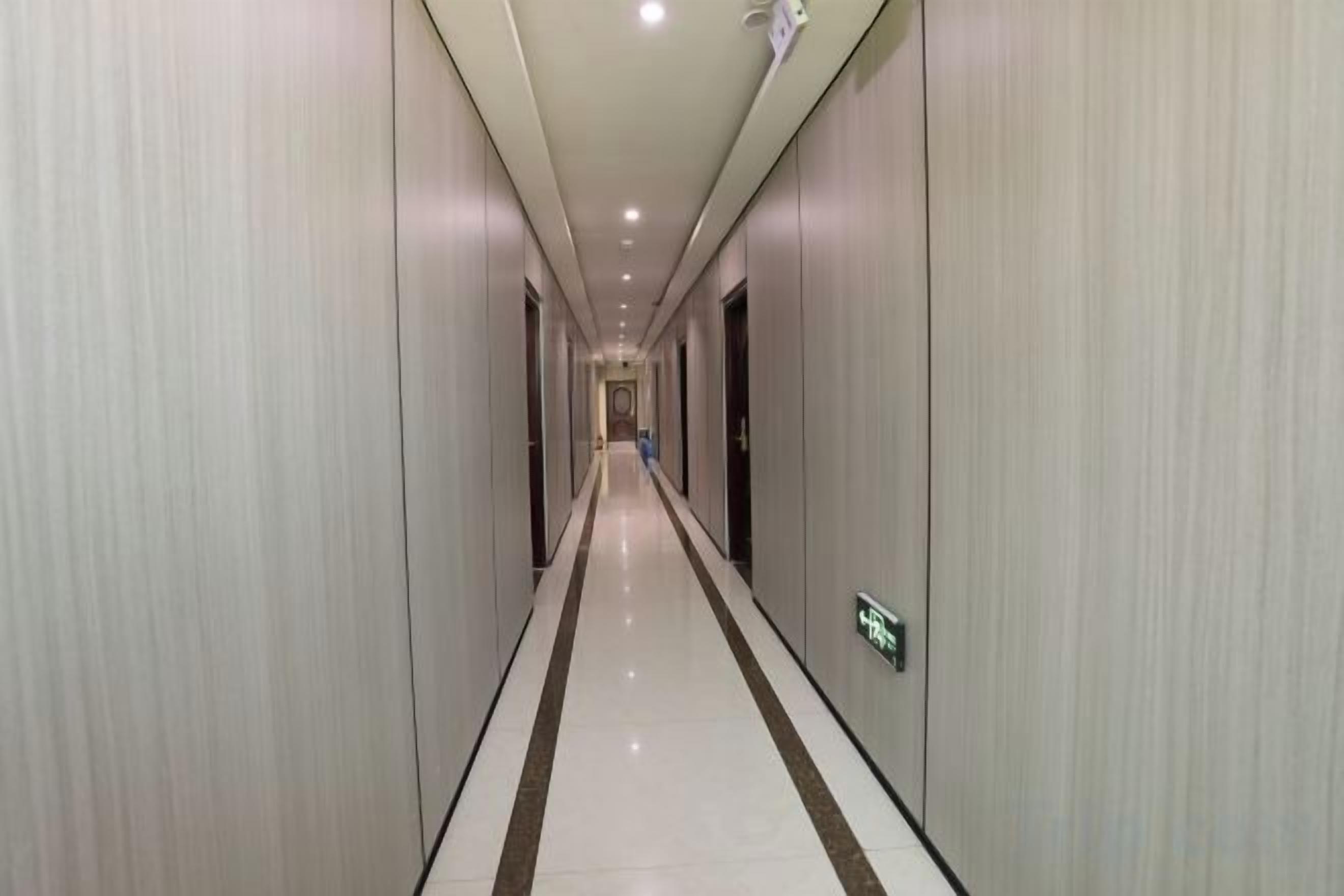 A long, narrow hotel corridor with doors on both sides and a central walkway.
