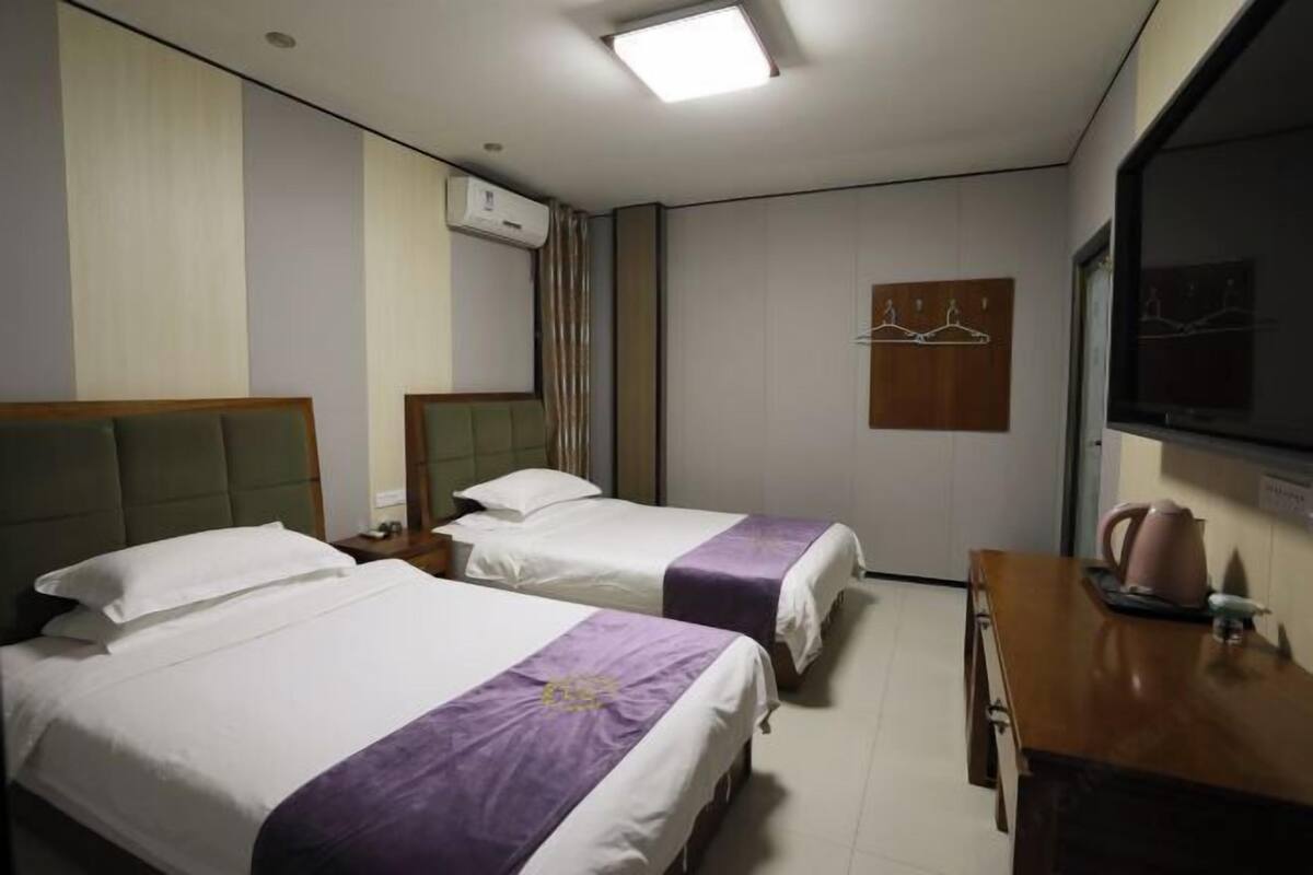 Une chambre d’hôtel avec deux lits, un bureau, une télévision et un appareil de climatisation.