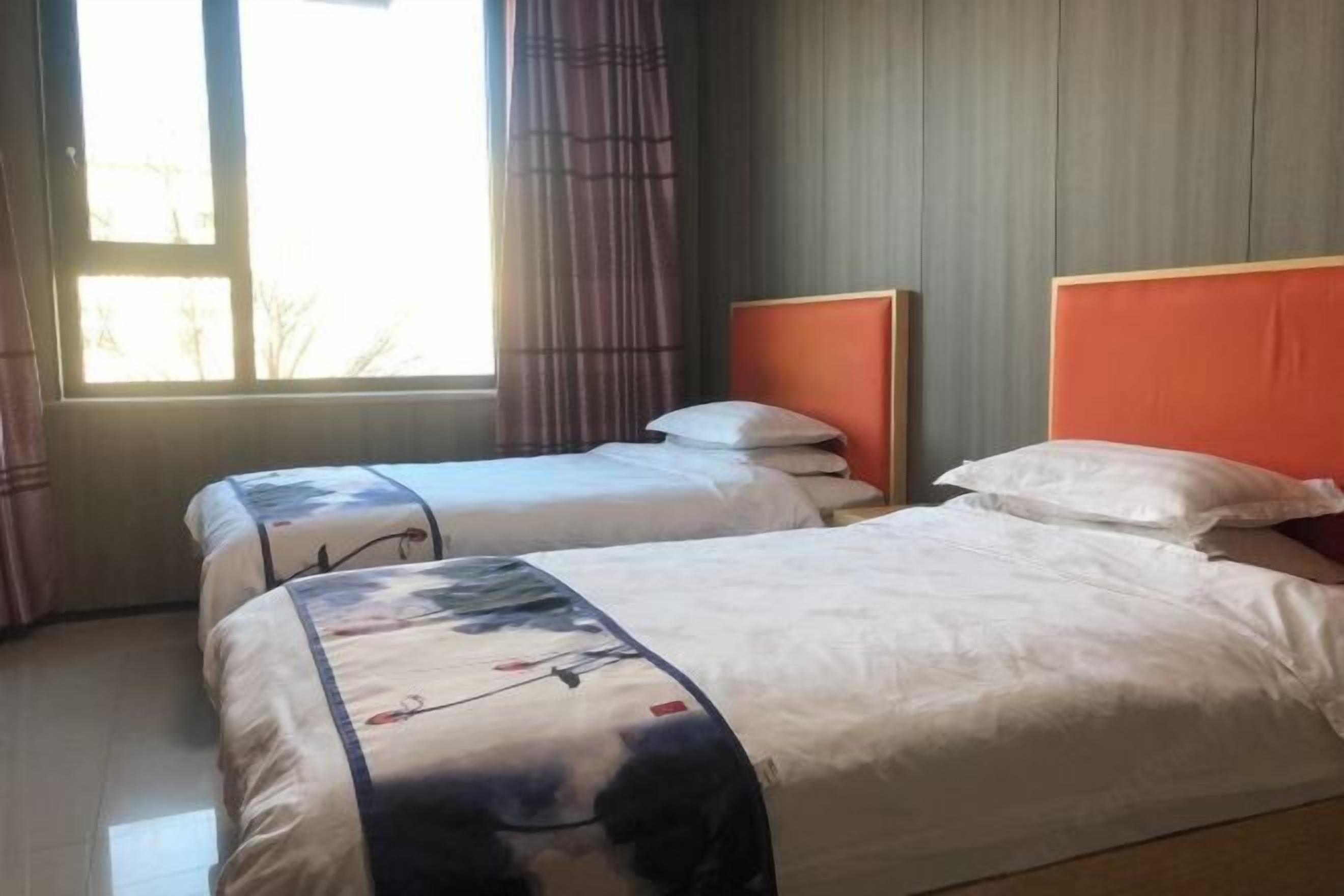 A hotel room with two beds, a window with curtains, and a wooden headboard.