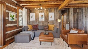 Ein gemütliches Blockhaus-Interieur mit einem Ecksofa, einem Lederhocker und einem braunen Ledersofa.