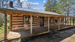 Eine rustikale Blockhütte mit Veranda, Schornstein und Tür.