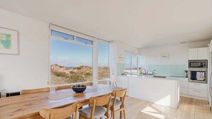 A modern kitchen with white cabinets, a built-in oven, and a view of the desert landscape.