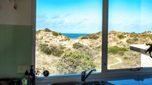 A room with a large window overlooking a coastal landscape.