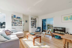 Uma sala de estar moderna com sofá, mesa de centro, TV e estantes.