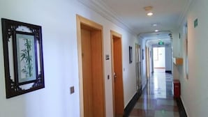 Un corridoio con porte in legno, opere d'arte incorniciate alle pareti e pavimento a scacchi.