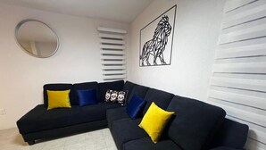 A living room with a dark-colored sofa set, a round mirror, and a framed artwork on the wall. - Nice, cozy, familiar and centrally located apartment (San Pedro Tlaquepaque)