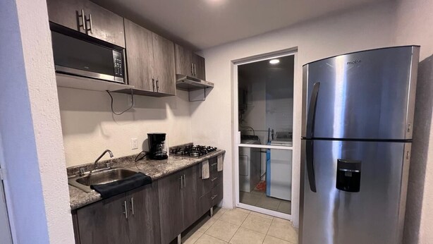 A compact kitchen with a stainless steel refrigerator, a microwave, and a gas stove. - Nice, cozy, familiar and centrally located apartment (San Pedro Tlaquepaque)