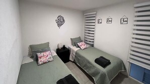 A small, clean room with two single beds, a nightstand, and a wall decoration. - Nice, cozy, familiar and centrally located apartment (San Pedro Tlaquepaque)