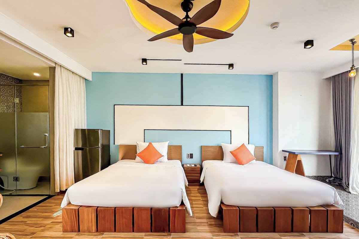 A modern hotel room with a large bed, a ceiling fan, a small table, and a view of the outdoors.