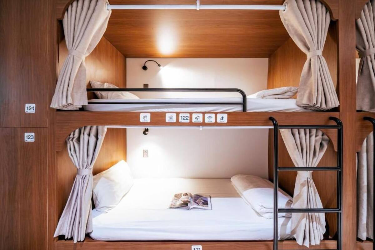 A bunk bed room with wooden walls, numbered beds, and curtains.