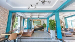 A spacious lobby with a reception desk, seating area, and a staircase leading to upper floors.