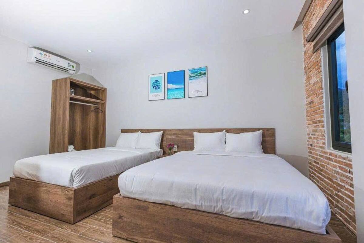 Habitación de hotel con dos camas, un armario de madera y una pared de ladrillo.