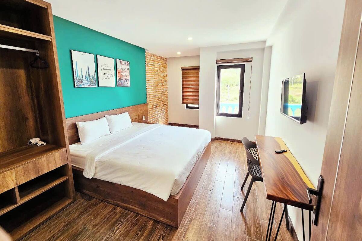 Un dormitorio con una cama de madera, un escritorio y un televisor.