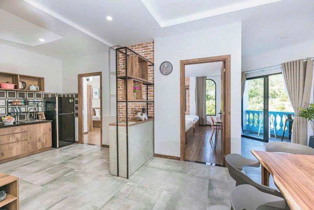 Uma cozinha moderna com parede de tijolos decorativa, área de jantar com mesa e cadeiras de madeira, e vista para uma varanda.