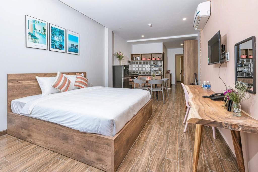 A bedroom with a wooden bed, a desk, and a kitchenette.