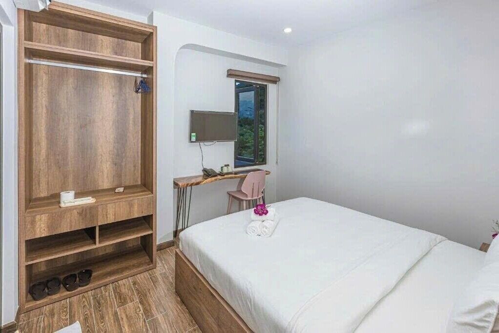 Un dormitorio con cama, armario de madera, escritorio y silla, y una ventana.