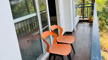 Enjoy a serene view of the lush landscape from this balcony, featuring two comfortable chairs and a small table.