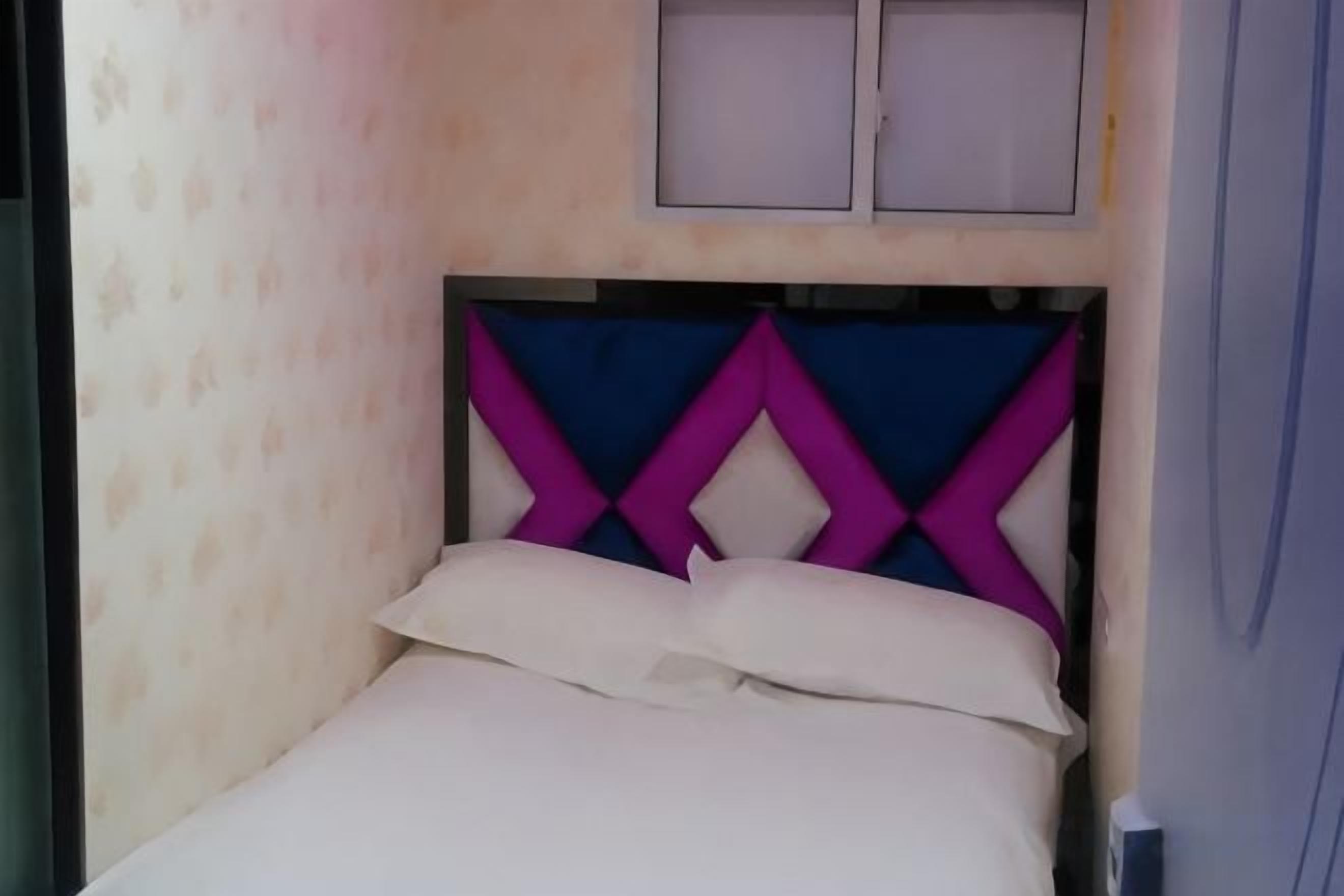 Cama com cabeceira com padrão geométrico, janela acima e parede com textura discreta.