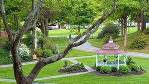 Un jardín con un pabellón, césped, árboles y un sendero.