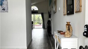 En hall med ett vitt konsolbord, en hundfigur och en dörr med ett svart handtag.