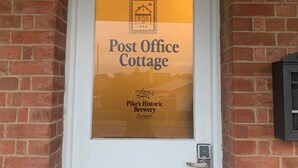A white door with a glass panel displaying 'Post Office Cottage' and 'Pike's Historic Brewery Oakbank' logos. - Post Office Cottage Oakbank, Adelaide Hills Wine Region, Pikes Historic Brewery (Oakbank)