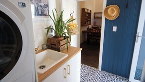A kitchen with a washing machine, a potted plant, and a blue door. - Post Office Cottage Oakbank, Adelaide Hills Wine Region, Pikes Historic Brewery (Oakbank)