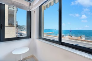 A room with a large window, a white sink, and a view of the sea and a distant island.