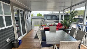 A covered patio with a table and chairs, a red sofa, and a potted plant.