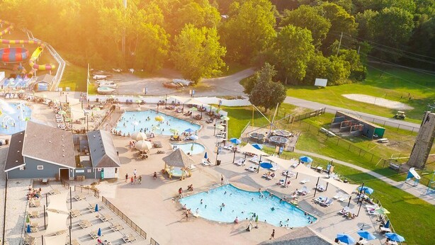 An aerial view of a resort with multiple swimming pools, a water park, and a golf course.