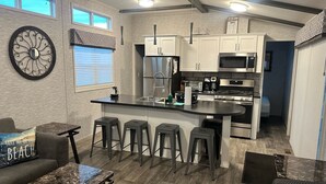 A modern kitchen with a central island, bar stools, and stainless steel appliances.