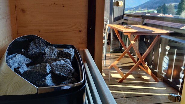 Un balcón con vistas a montañas, una mesita y un bote de carbón.