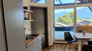 Una cocina moderna con un ventanal grande, suelo de madera y un comedor con mesa y sillas.