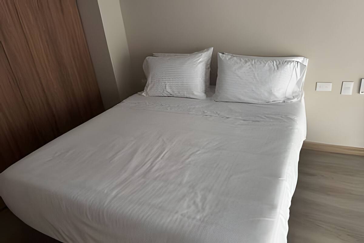 A neatly made bed with white linens in a hotel room.