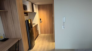 A modern kitchen with wooden cabinets, a stainless steel refrigerator, and a microwave. - Vivo52 (Bogotá)