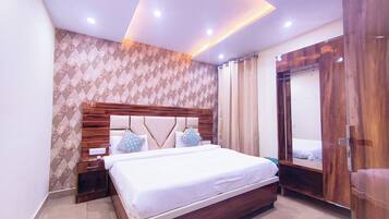 A modern bedroom with a large bed, wooden headboard, and a nightstand.