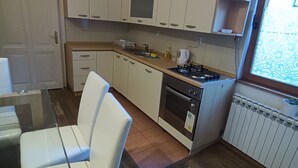 Una cucina compatta con zona pranzo, dotata di forno a incasso, microonde e finestra con tende a motivi.