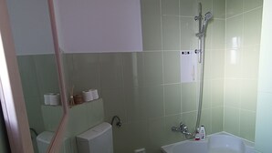 Un bagno con un lavandino bianco, uno specchio, un water e una zona doccia.
