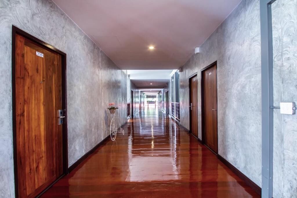 A long, polished hallway with wooden doors on both sides, leading to a bright, open space at the end.