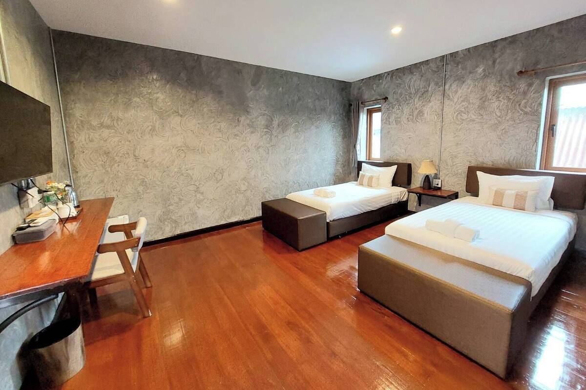 A hotel room with two beds, a desk, and a chair.
