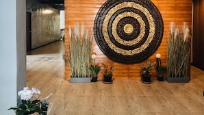 A wooden wall with a circular decorative piece and potted plants. - Momento House (Ayutthaya)