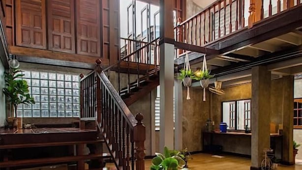 A spacious interior with a wooden staircase, large windows, and a potted plant. - Momento House (Ayutthaya)