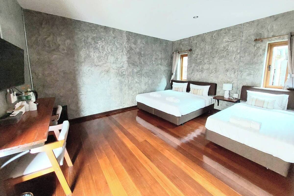 A hotel room with two beds, a wooden desk, and a large mirror.