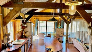 A rustic cabin interior with a wooden dining table, kitchen area, and a sofa. - Stunningly built open-plan Studio in natural pastureland setting (Hay Valley)