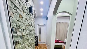 A hallway with a stone wall, wooden flooring, a door, and a bed in the background. - Lodging Vista hermosa (Esquipulas)