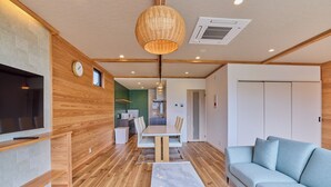 A modern living room with a wooden floor, a sofa, a dining table, and a TV. - Miire Mt.Fuji Forest (Fujikawaguchiko)
