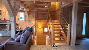 Een houten interieur met een trap, een bank en een open haard.