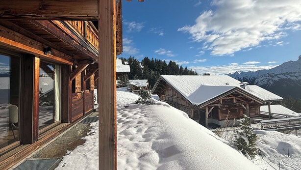 Een houten hut met grote ramen en een besneeerd landschap.