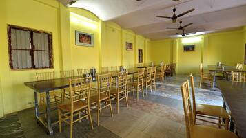 A dining area with multiple tables and chairs, ceiling fans, and framed pictures on the walls.